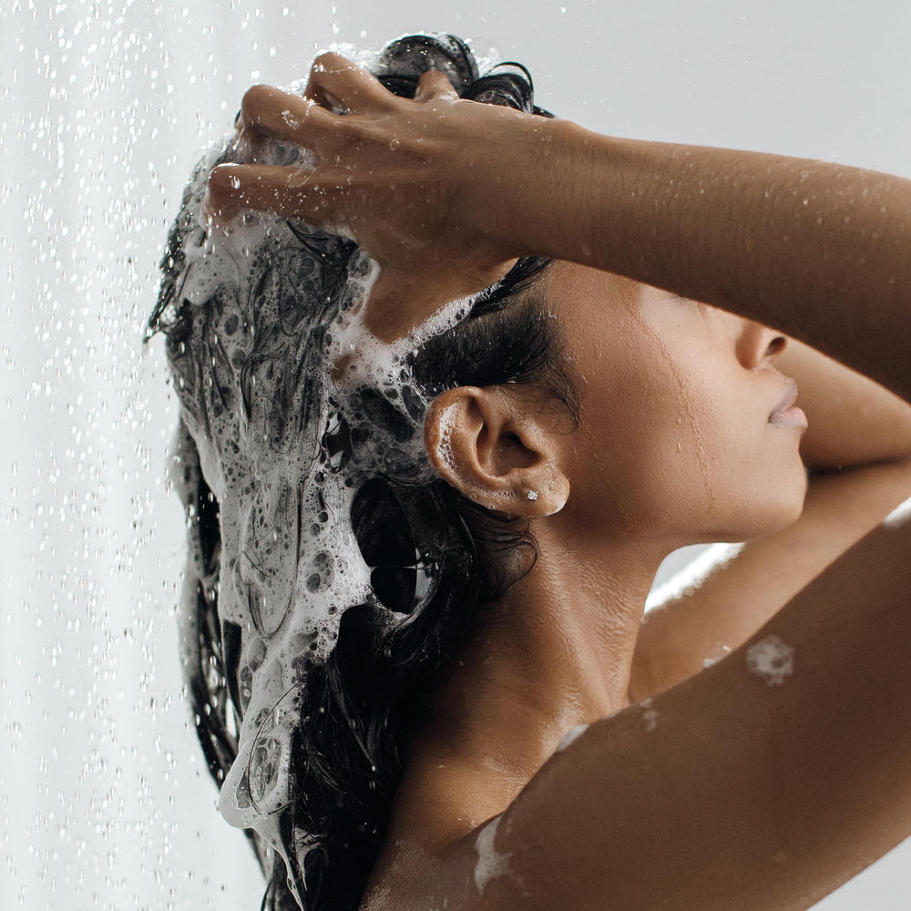 Kristin Ess shampoo on bathroom shelf conveying curated, salon-style routine