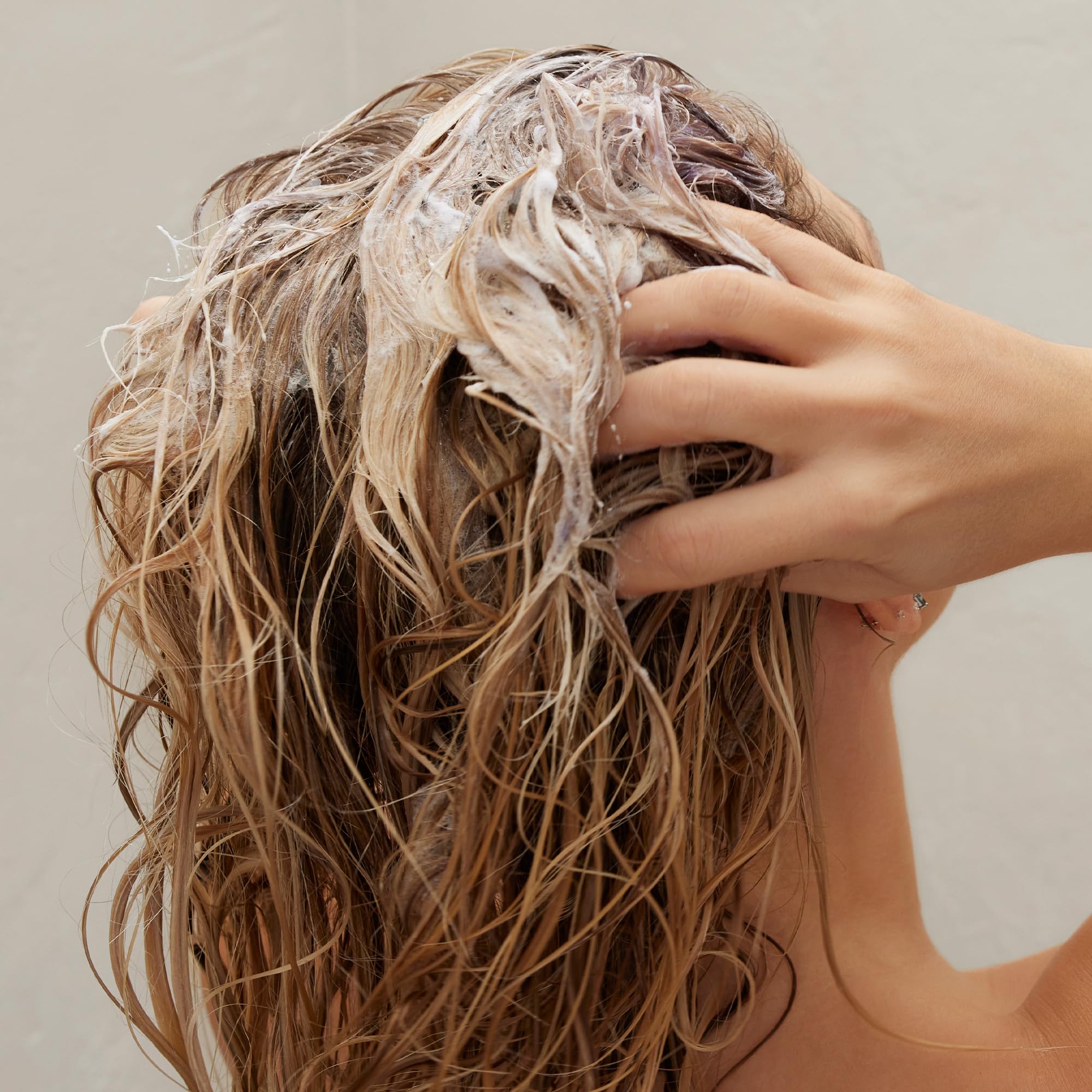 Kristin Ess shampoo in use on wet hair showing visible toning action and shine