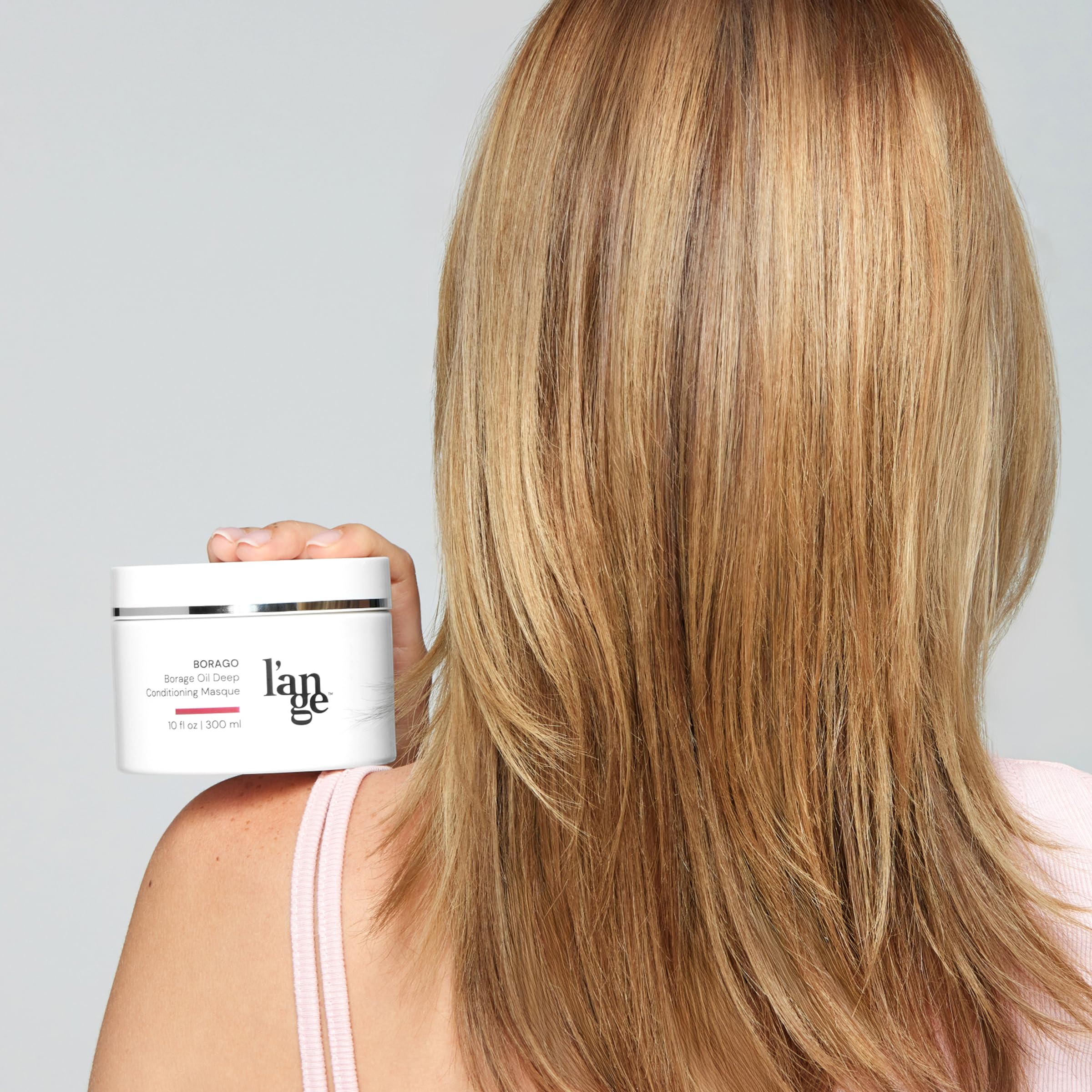 L'ANGE HAIR 10 oz tub next to hand to show size and travel convenience