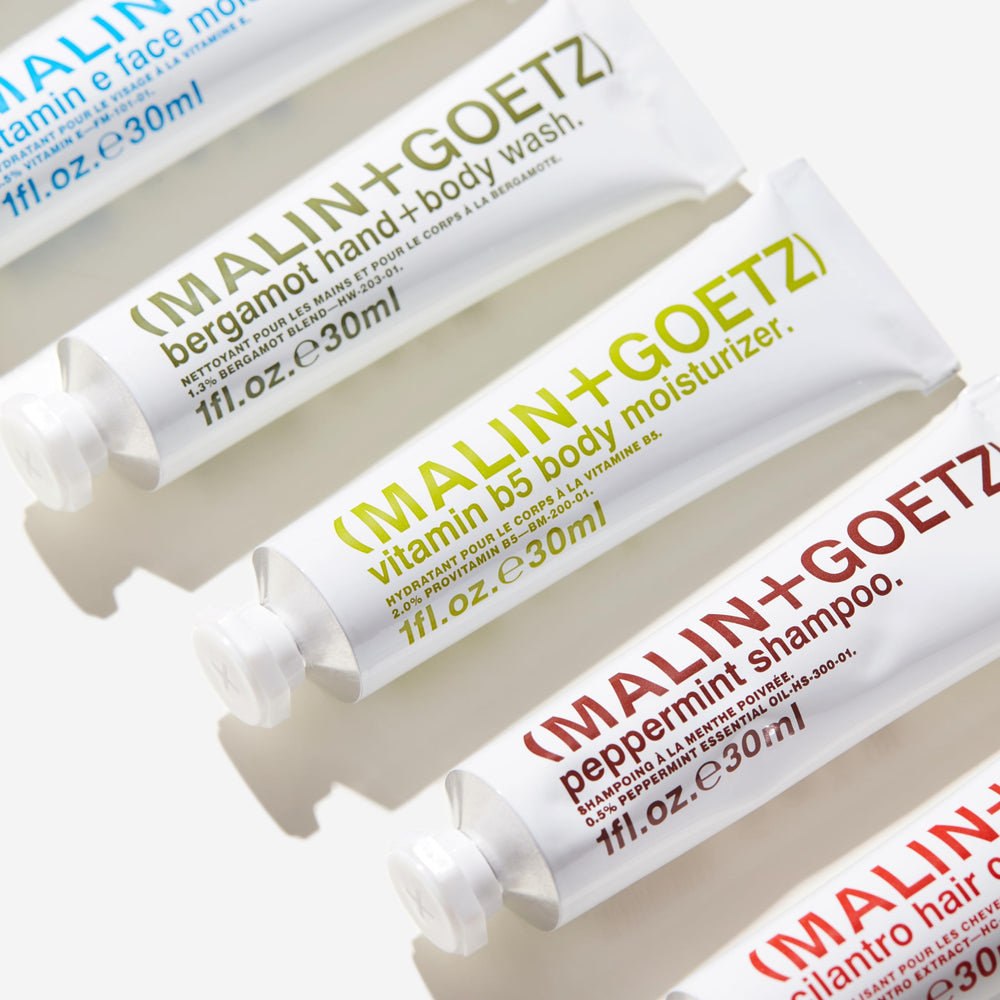 MALIN+GOETZ travel kit beside a passport to show TSA-friendly 1 oz scale