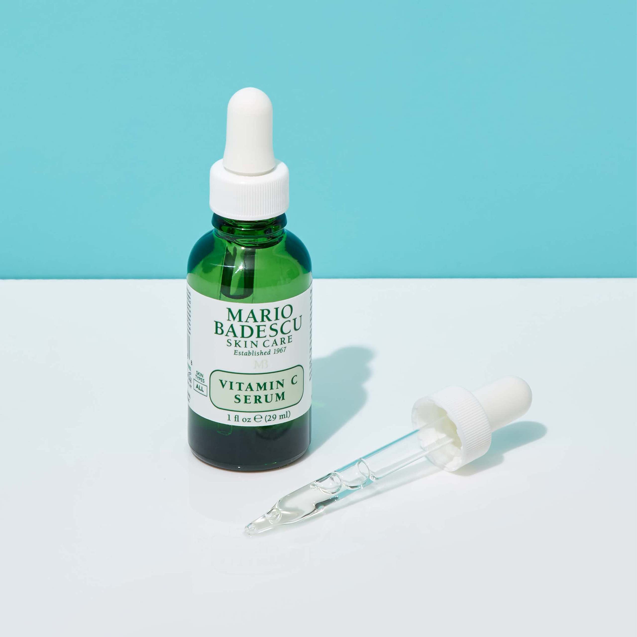 Mario Badescu next to a common 1 oz scale to show actual bottle size and travel-friendly benefit