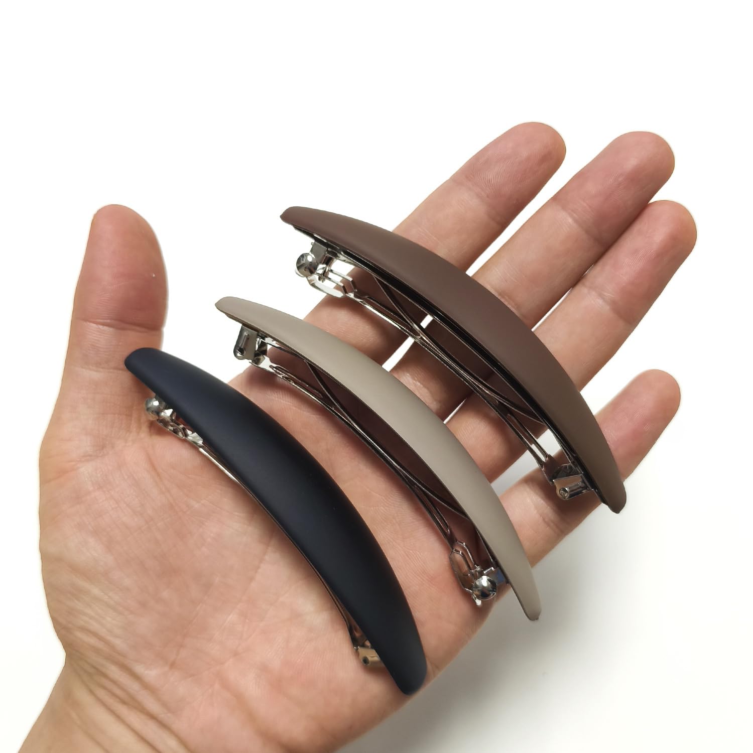 Markuii barrette held in hand to show 4-inch scale and easy handling