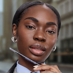 Maybelline model applying eyebrow pencil in front of bathroom mirror