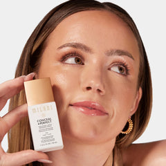 Fingers blending Milani bronzing drops demonstrating easy application and streak-free finish