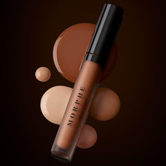 Morphe concealer bottle beside fingers to show compact travel-friendly size