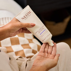 Neom body butter on hand demonstrating smooth spread and instant nourishment