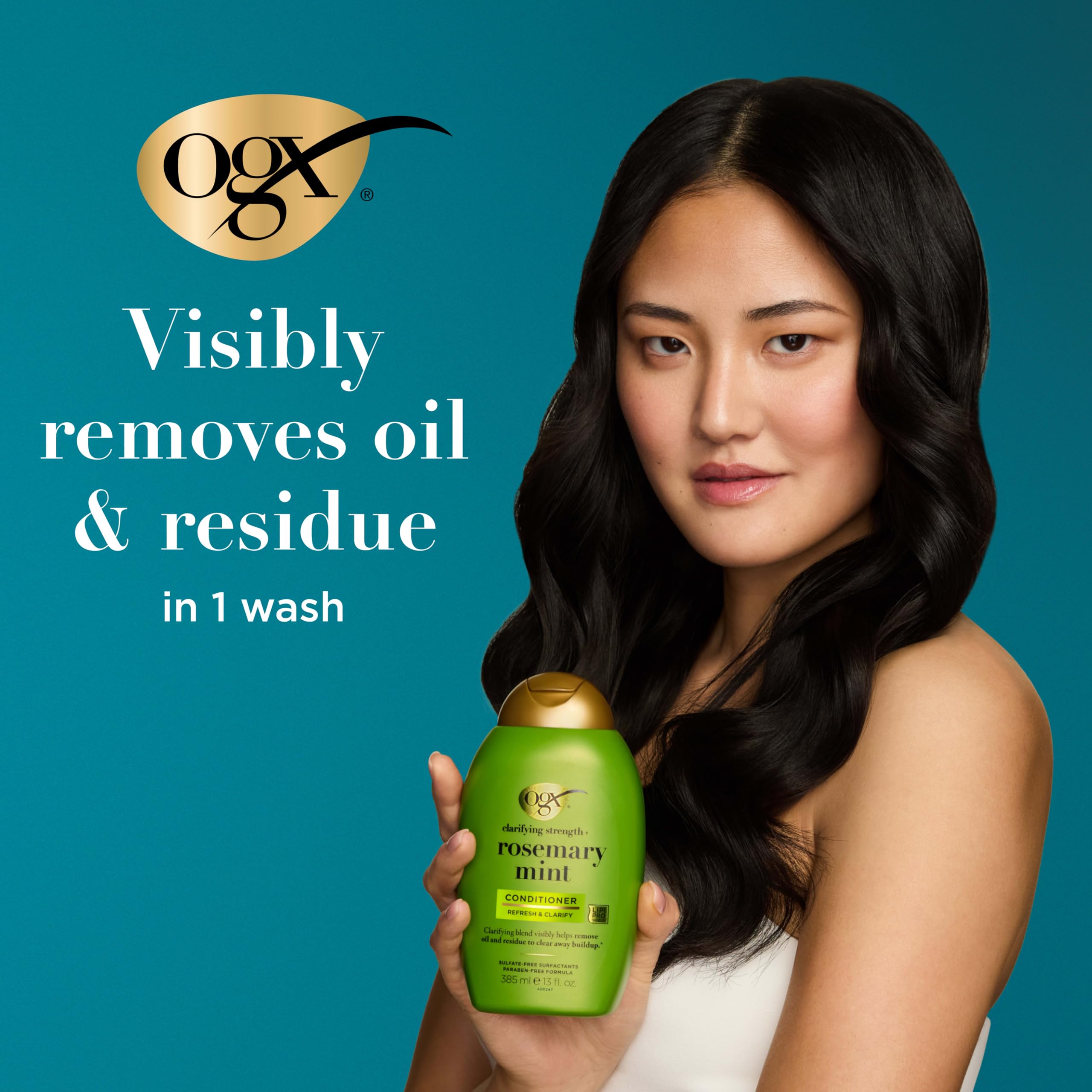 OGX bottle held next to hand to display 13 fl oz size and portability benefit