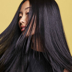 Oribe bottles in hand to show travel-size scale and portability