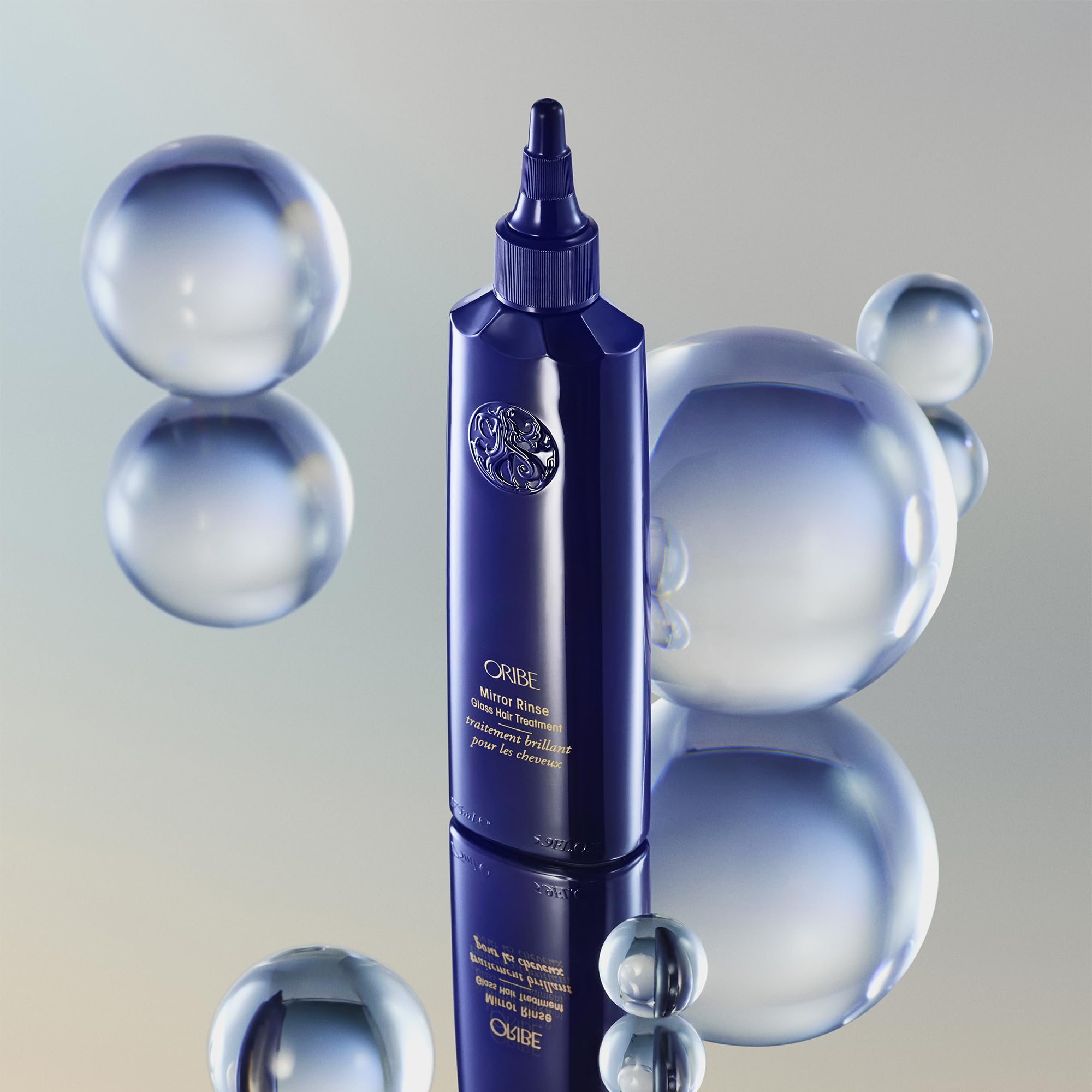 ORIBE stylist applying treatment to hair demonstrating frizz control and gloss benefit