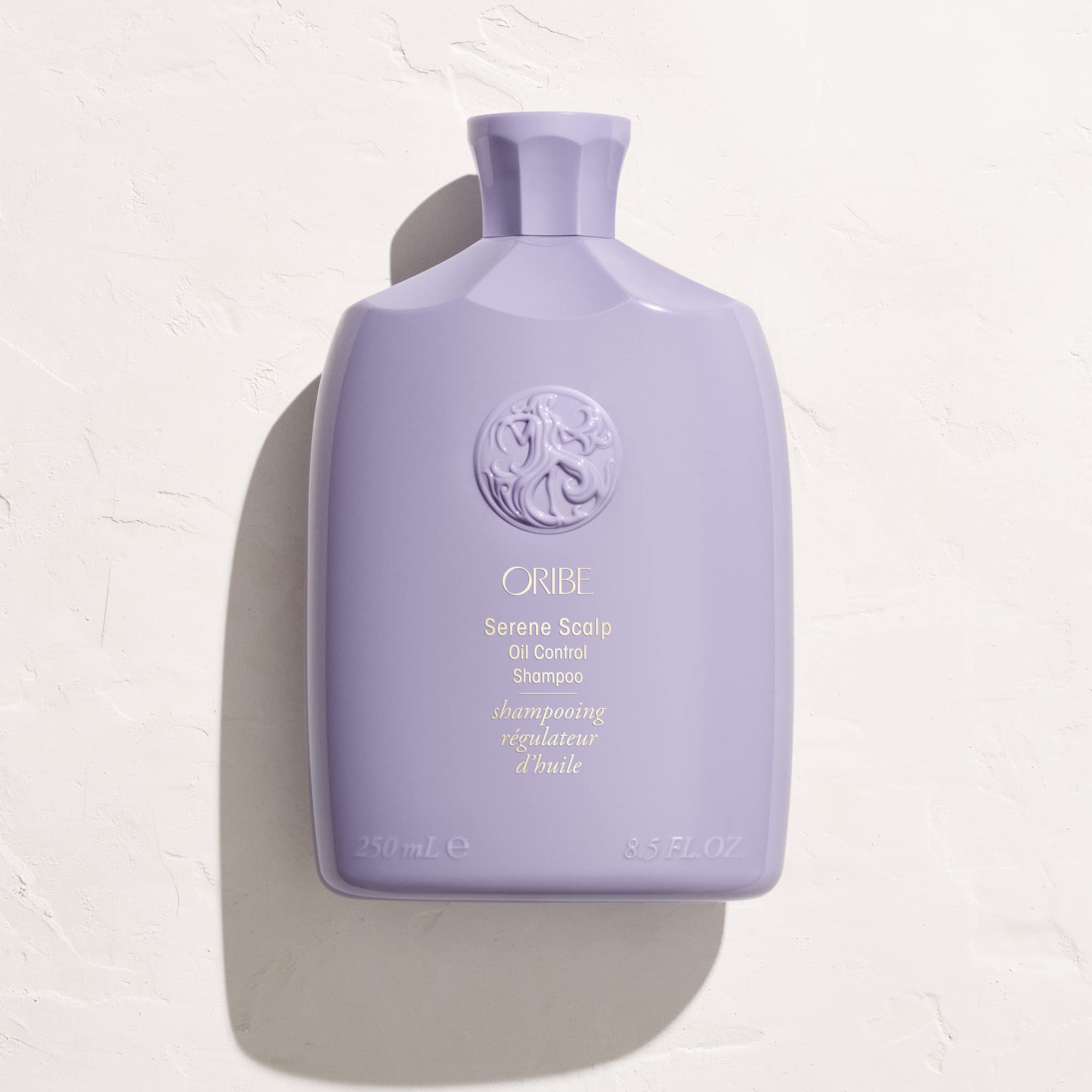 ORIBE bottle in hand during application demonstrating simple at-home use