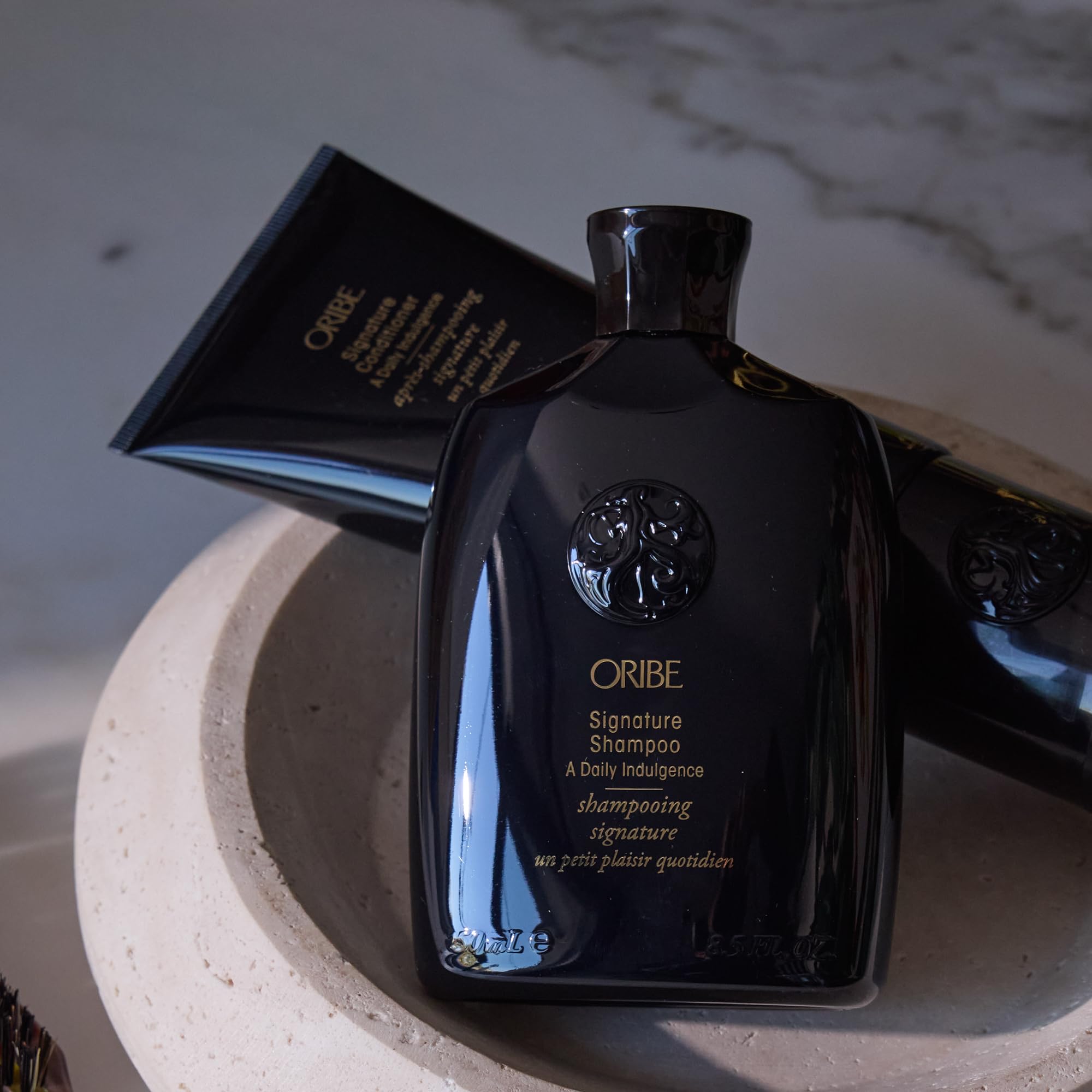 Oribe signature shampoo on a bathroom shelf in lifestyle scene conveying premium ritual benefit