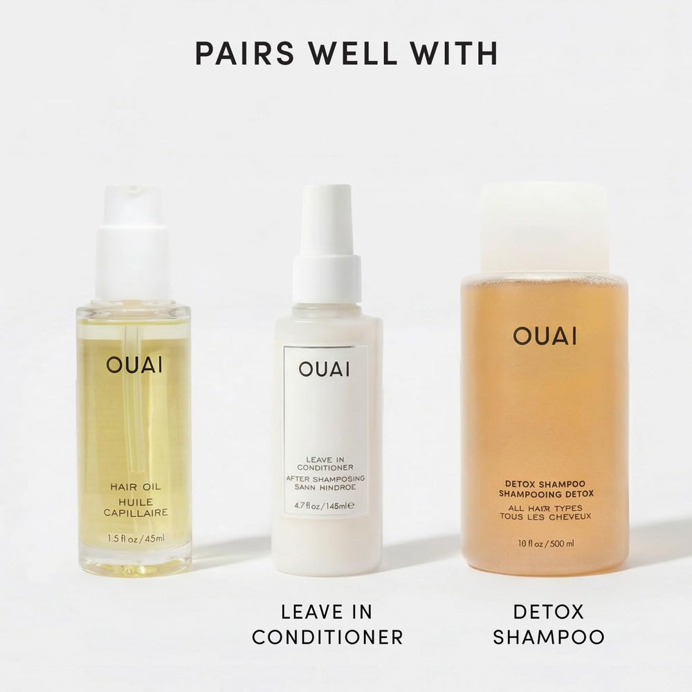 OUAI bottles in hand for scale comparison showing compact travel size and full-size utility