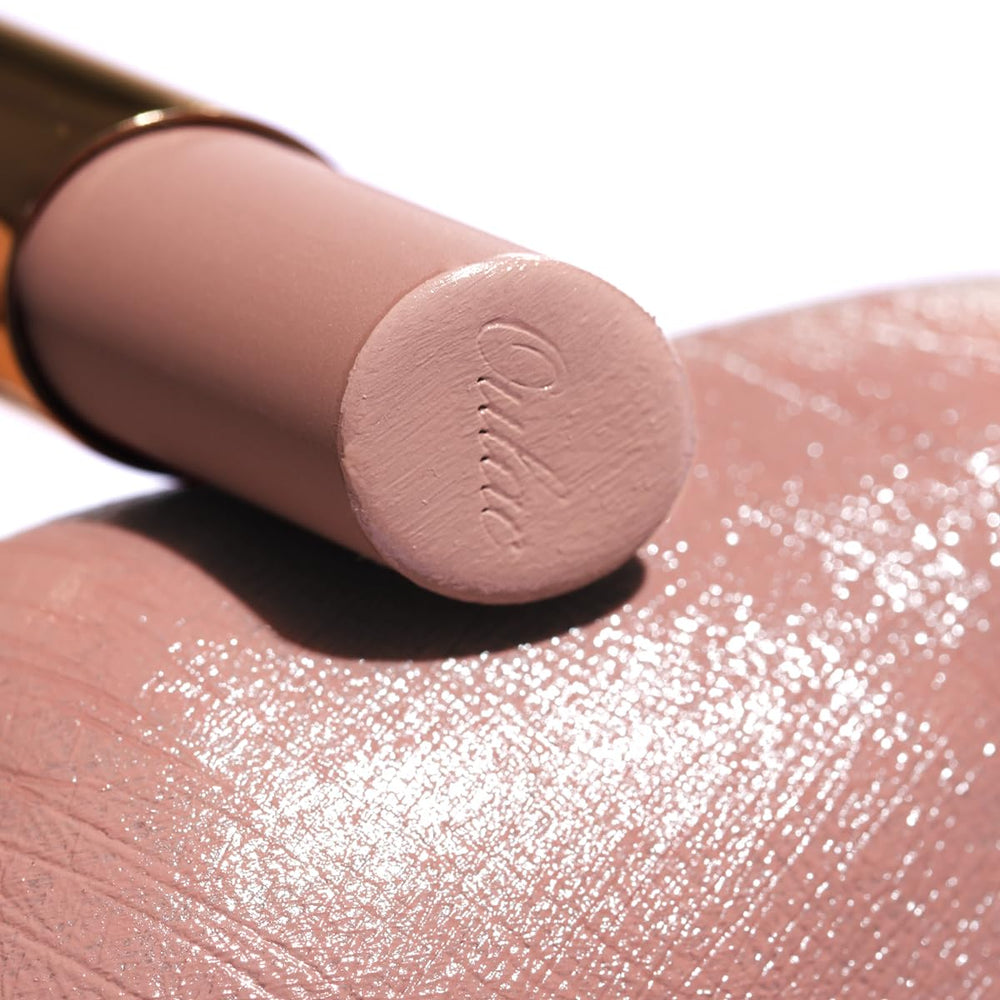 Oulac lipstick next to coin demonstrating compact travel-friendly size