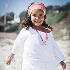 Peppercorn Kids headband beside a hand showing scale and child-friendly size