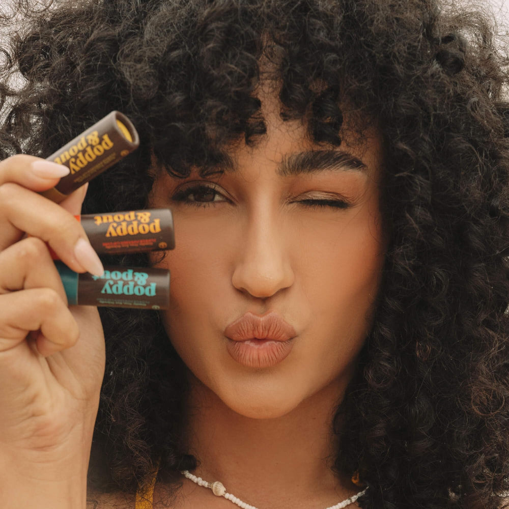 Poppy & Pout tube on vanity with plants highlighting natural ingredients