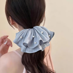 Qojai scrunchie held in hand to show scale and suitability for thick hair