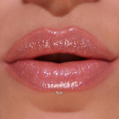 Revolution Pout Bomb texture swatch on skin demonstrating hydrating shimmer finish