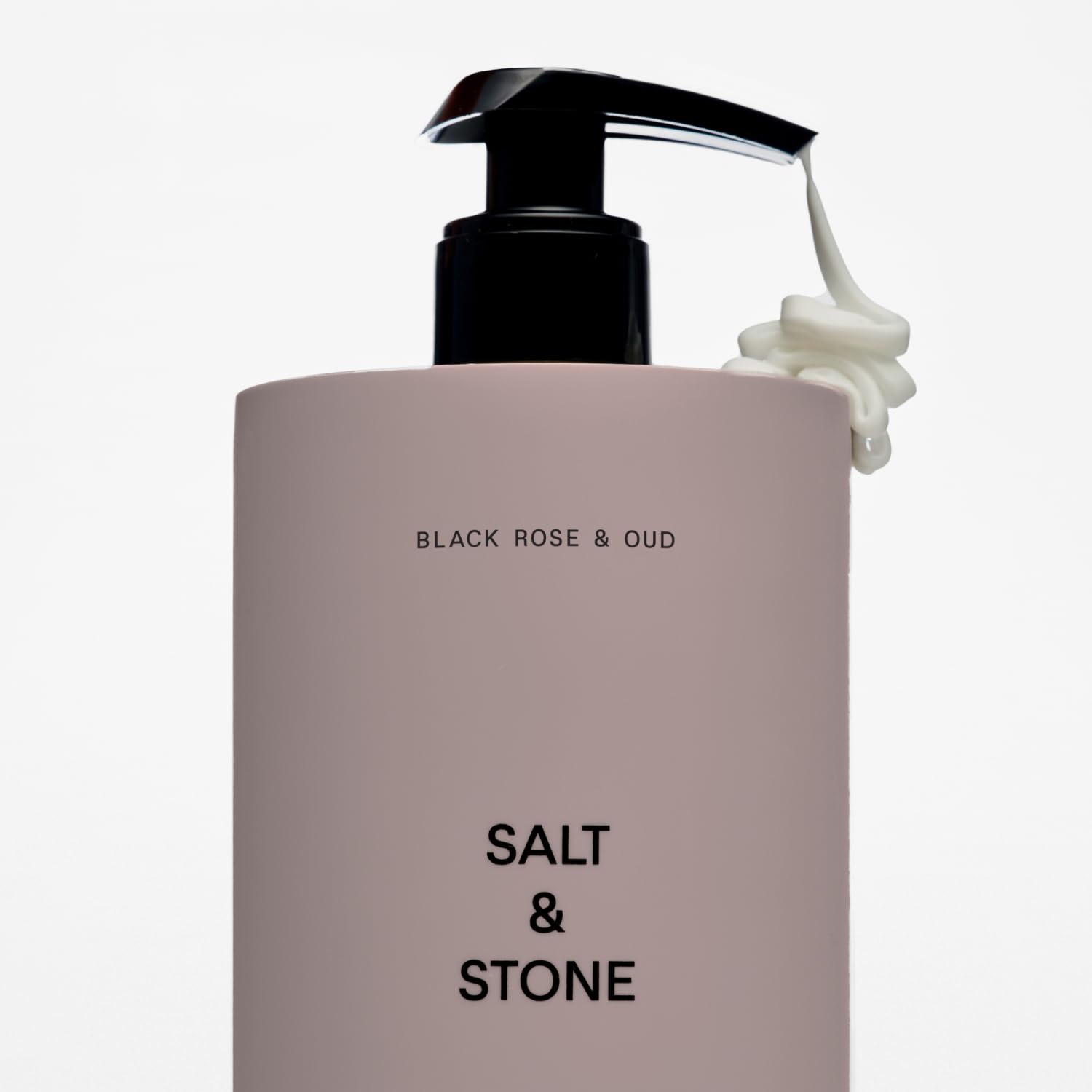 Salt & Stone bottle beside hand for scale showing 15.2 fl oz size