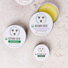 Savannah Bee Company tin beside fingers to show compact size and single-hand use benefit