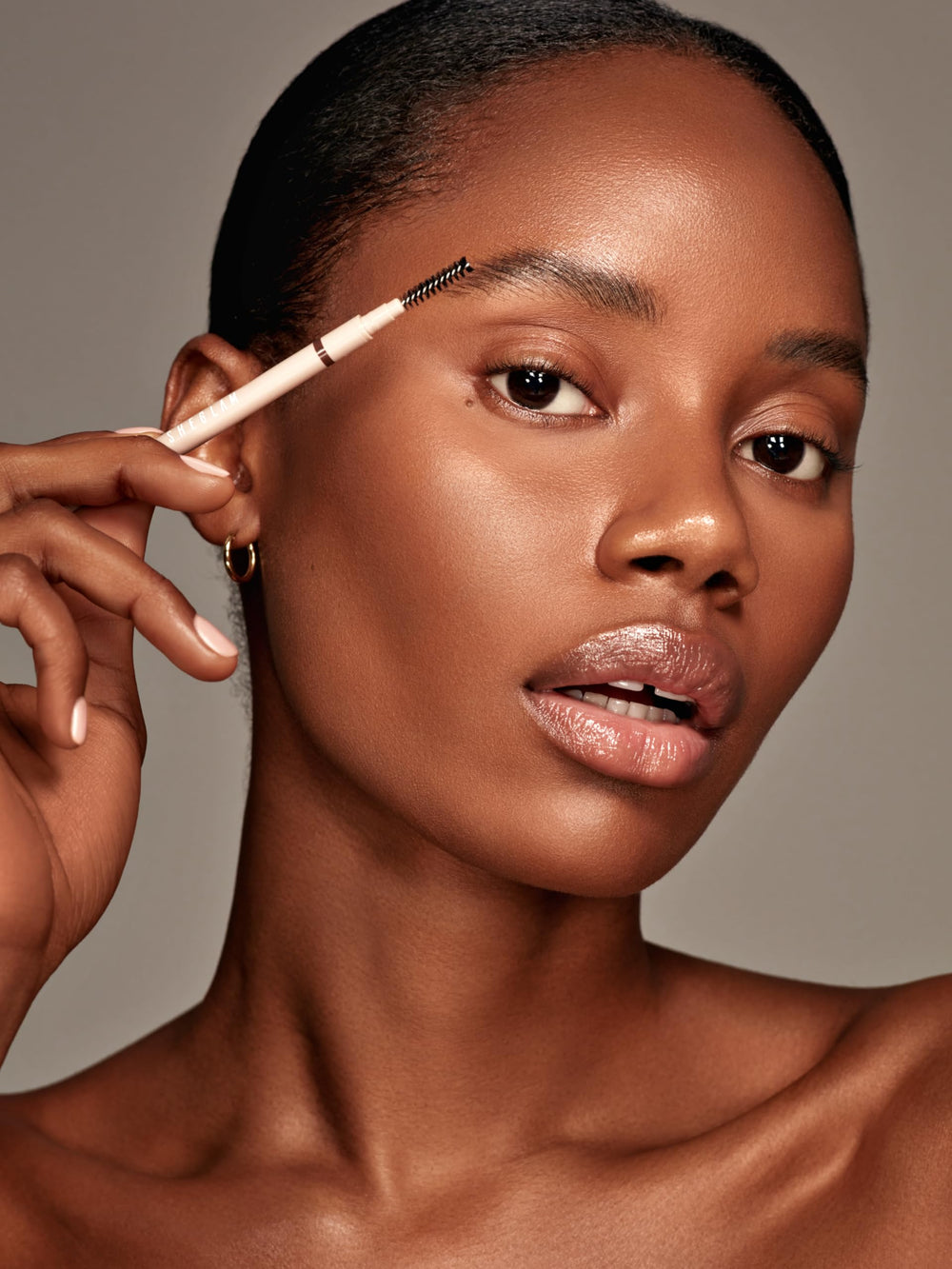 SHEGLAM pencil held next to coin to show compact size for travel-friendly touch-ups