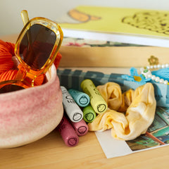 Sun Bum cocobalm next to a coin for size comparison showing compact tubes perfect for pockets and purses