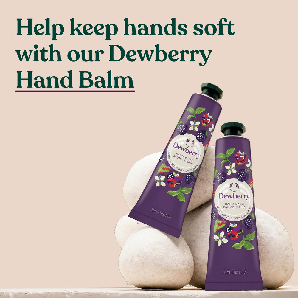 The Body Shop Dewberry hand balm 30ml tube held next to a coin to show travel-friendly size benefit