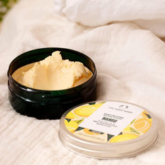 The Body Shop mango body butter with fresh mango cut to suggest juicy tropical fragrance