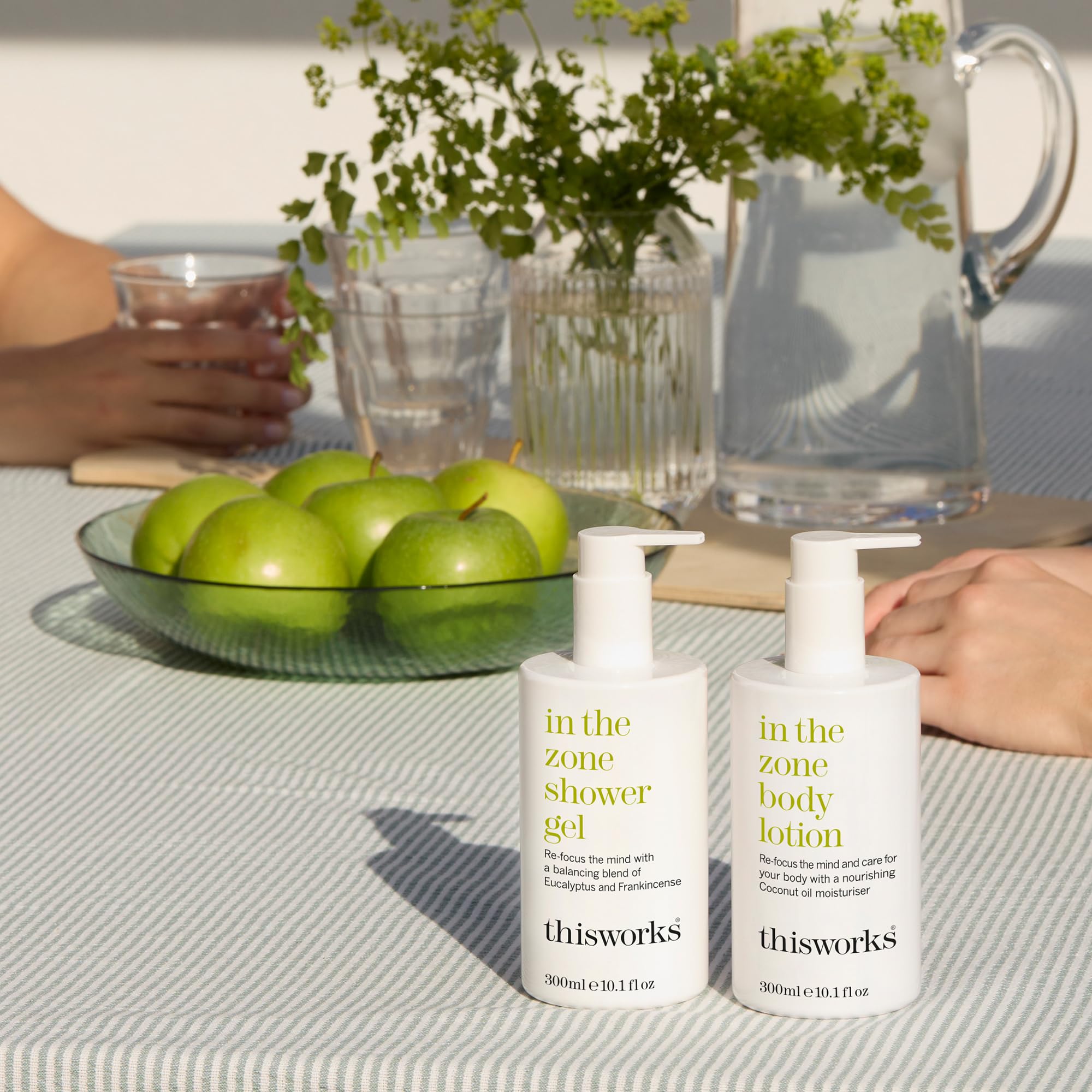 THISWORKS bottle next to common items to show 300ml scale and travel convenience