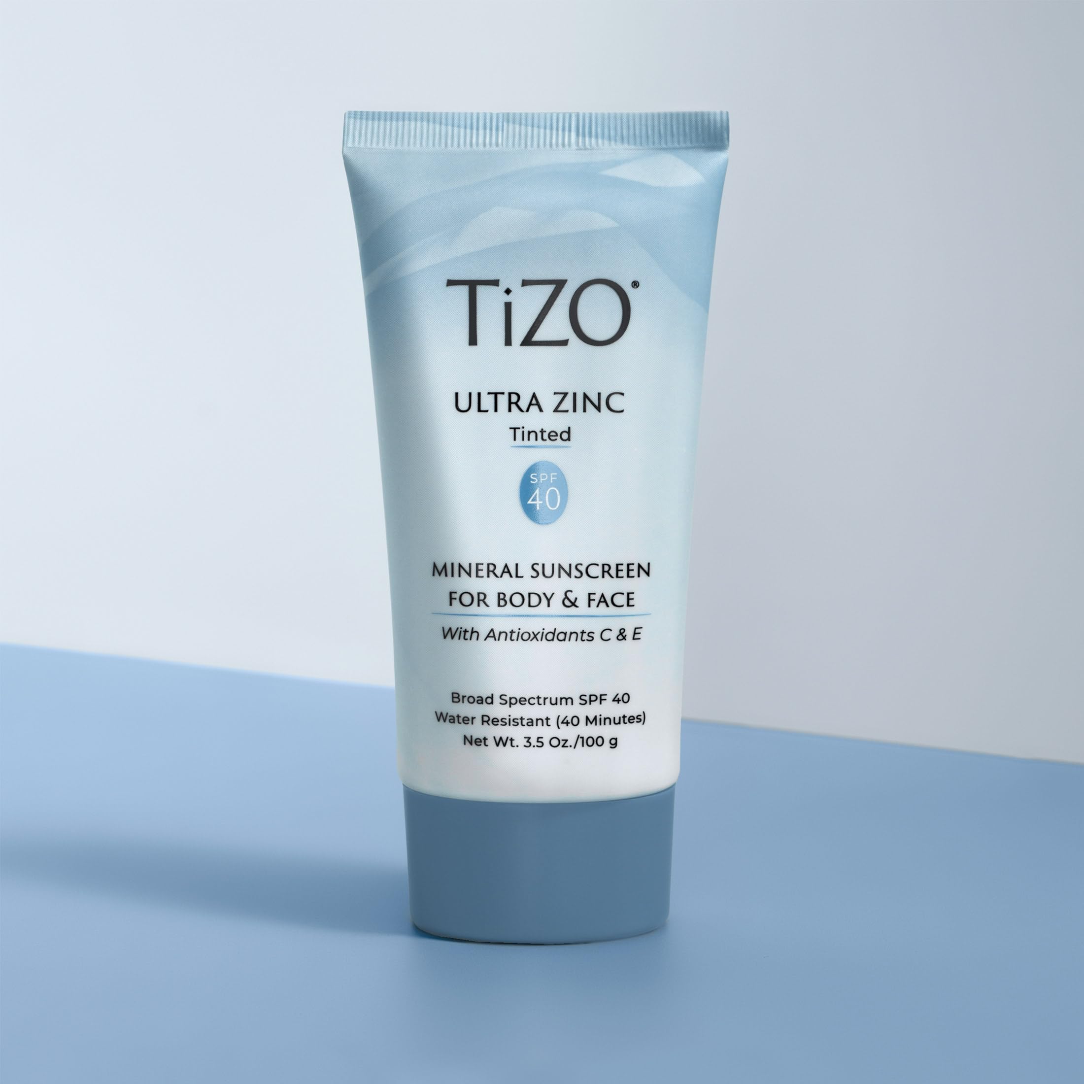 TIZO tube beside a hand for scale showing 3.5 oz size