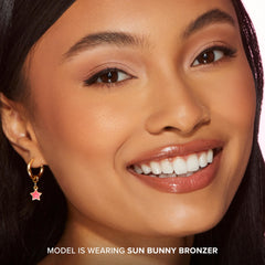 Too Faced Sun Bunny in a beach bag lifestyle shot suggesting travel-friendly glow