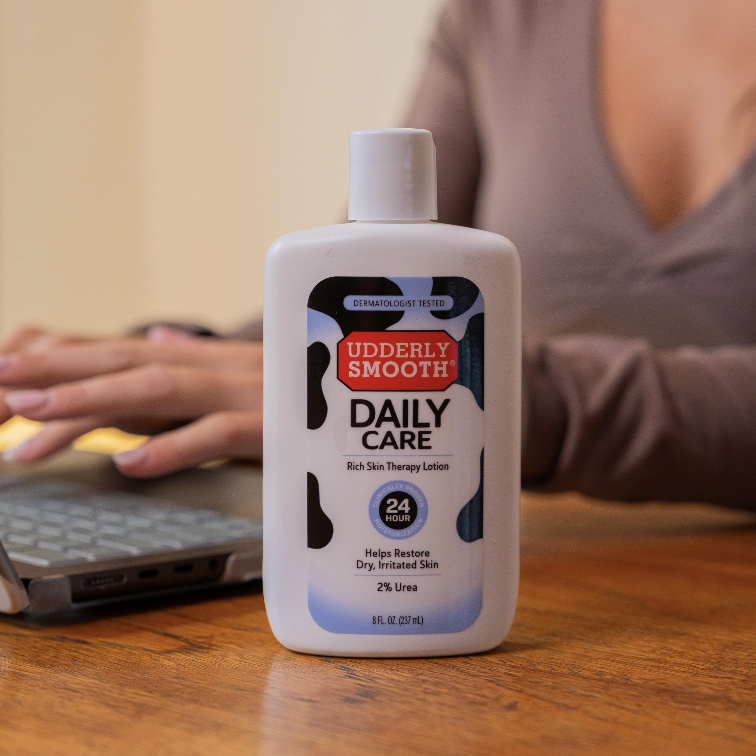UDDERLY SMOOTH 8 fl oz bottle beside hand for scale showing portable benefit