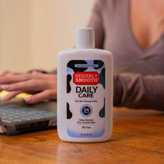 UDDERLY SMOOTH 8 fl oz bottle beside hand for scale showing portable benefit