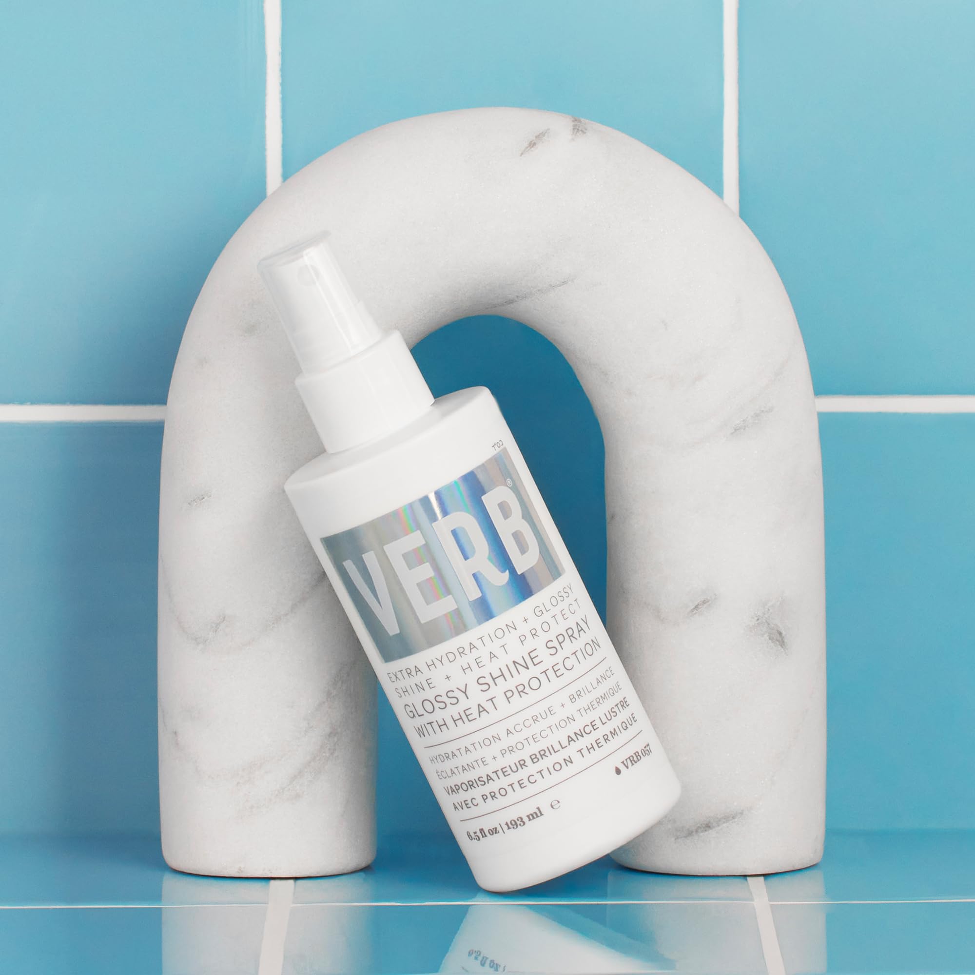 VERB Glossy Shine Spray next to a ruler showing 2 fl oz size for travel-friendly portability