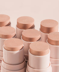 Wander Beauty stick beside coin to show size and portability benefits