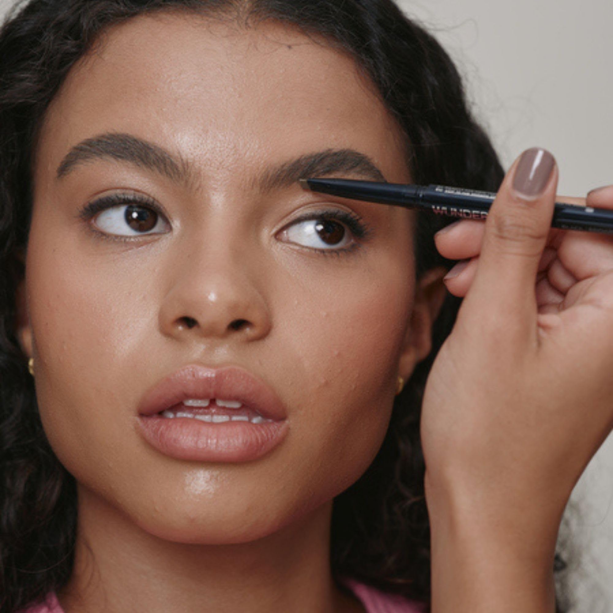 WUNDERBROW dual pencil held in hand to show compact travel-ready scale